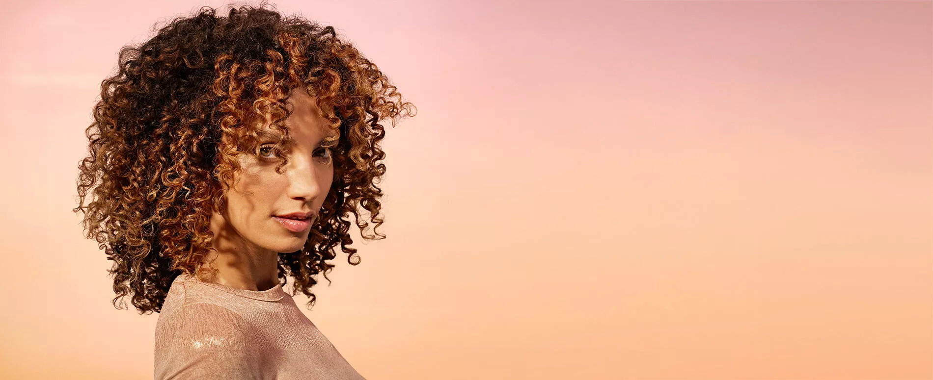 mixed race woman with ombre brown to honey blonde curly hair